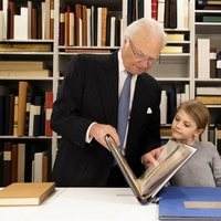 Carlos Gustavo de Suecia enseña un libro a Estela de Suecia junto a Victoria de Suecia en la Biblioteca Bernadotte