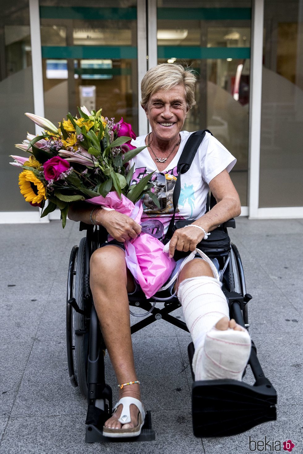 Chelo García Cortés saliendo del hospital con un ramo de flores