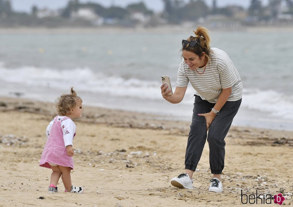 Toñi Moreno, haciendo una foto a su hija Lola en la playa