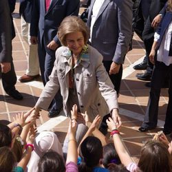La Reina Sofía saluda a unos niños durante su visita a los afectados por las inundaciones en Málaga