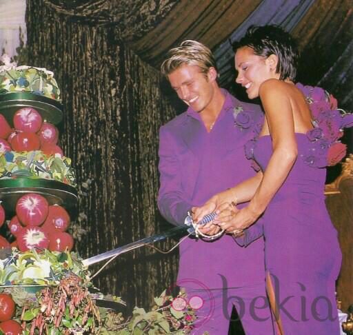Victoria y David Beckham partiendo la tarta en su boda